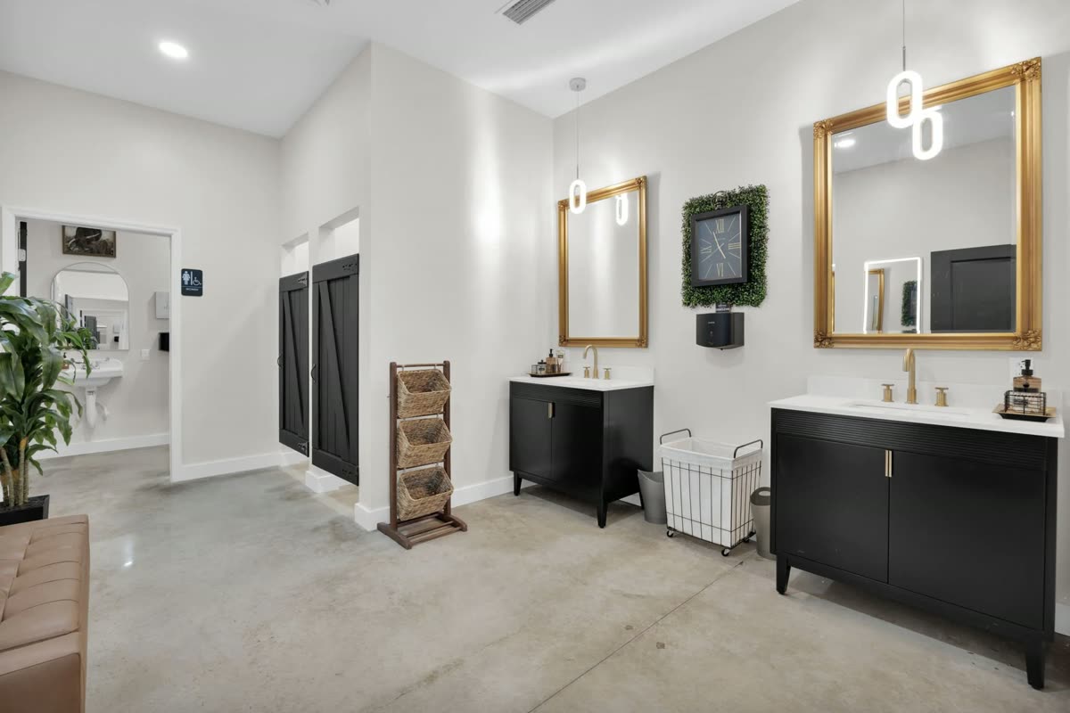 The bridal suite vanity, gold-framed mirrors above black cabinetry in a bright white room