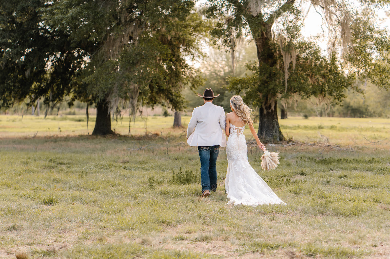 A couple walking hand in hand through the golden oak pasture at sunset