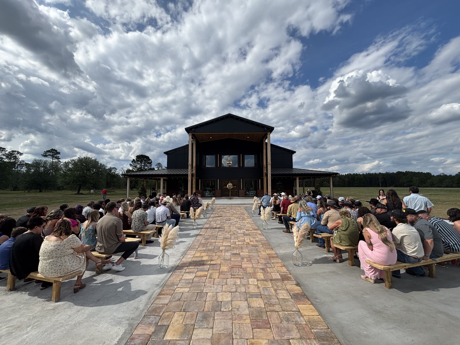 The paver ceremony aisle lined with benches leading to The Venue's facade